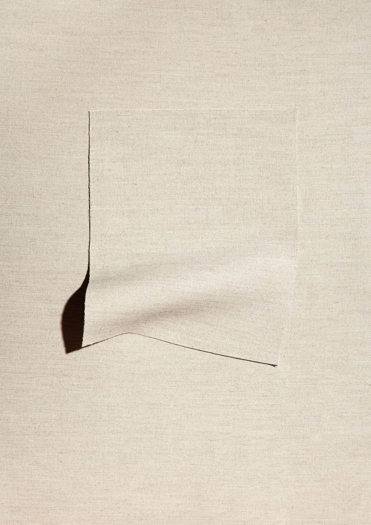 A square of natural cotton fabric with a curled corner
